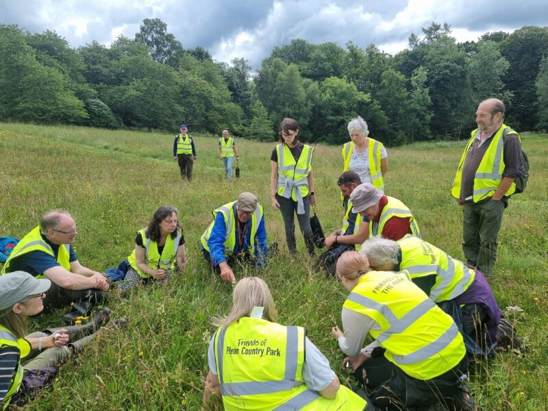 A group of volunteers gathered round Roy Sexton as he explains the pollination process for the Greater Butterfly Orchid